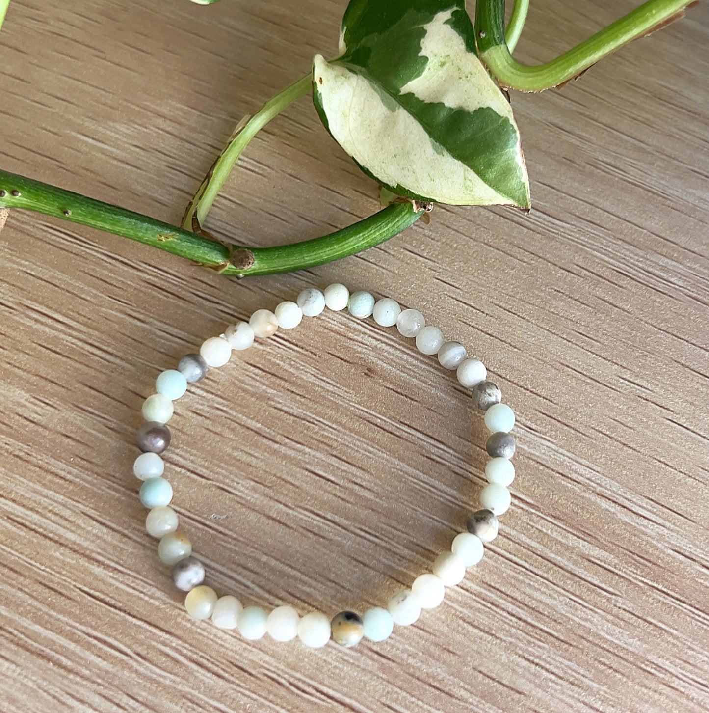 Amazonite Beaded bracelet on a wooden surface with green leaves in the background