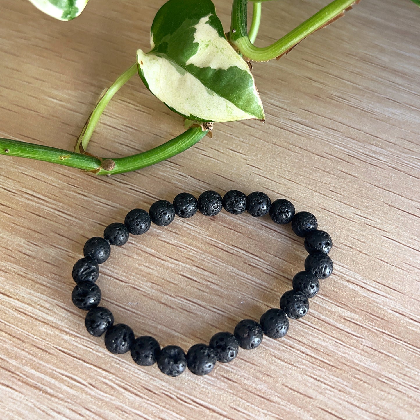 Kids Lava Stone bracelet on a a wooden surface with green leaves in the background