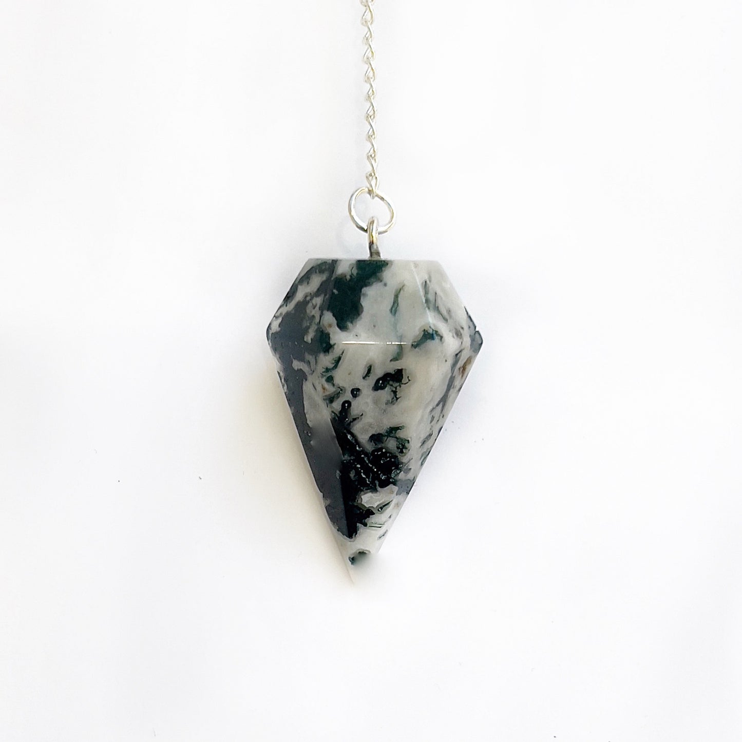 A tree agate pendulum with a silver chain, displaying a pattern of green foliage-like inclusions against a milky white background. The pendulum is shaped into a pointed, faceted geometric form that tapers towards the bottom, creating a sleek, elegant appearance. | Simply Esoteric