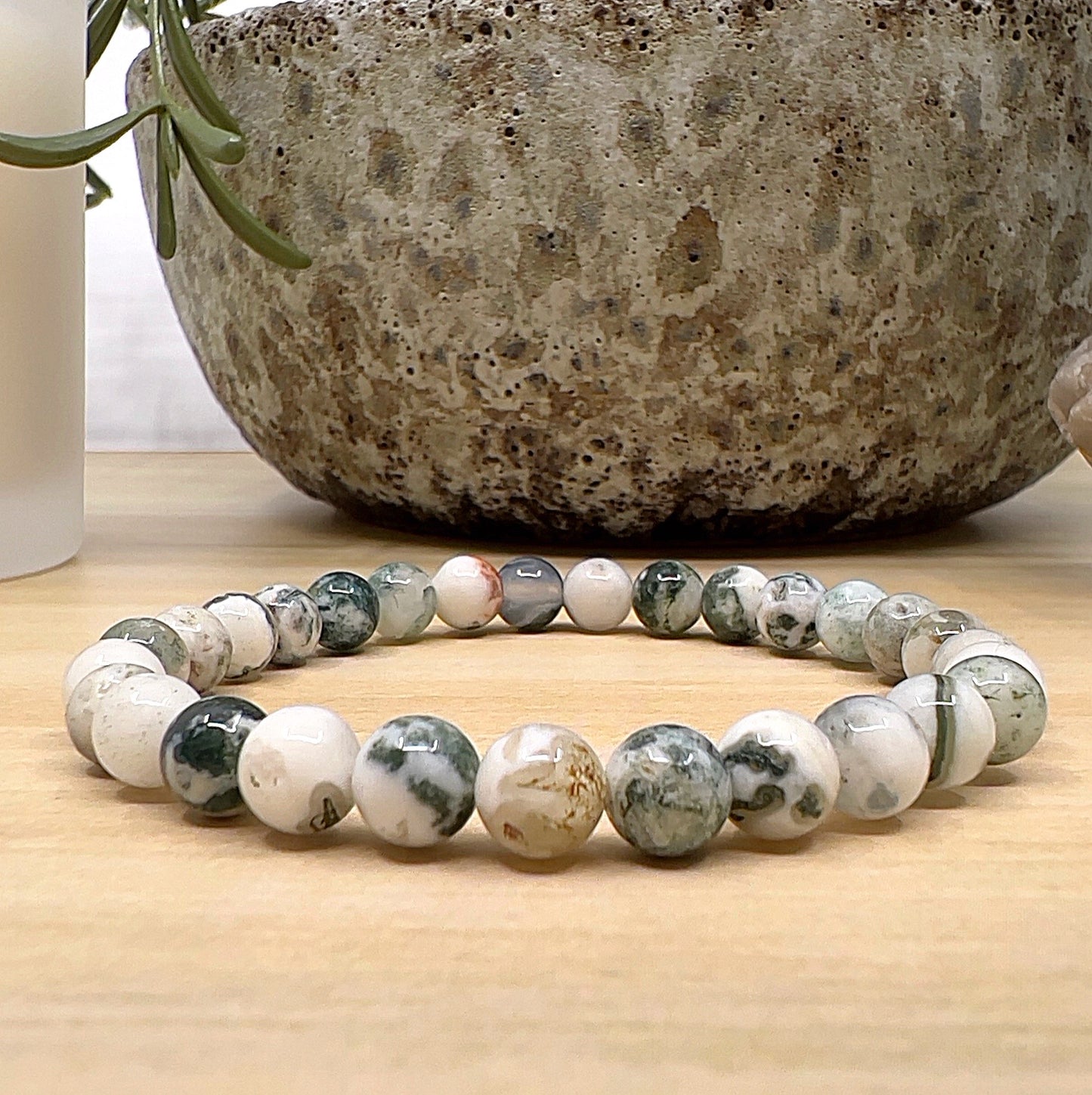 Handmade Tree Agate crystal bead bracelet with 6mm round beads on stretchy cord, featuring creamy white and green patterned stones, displayed on a wooden surface. | Simply Esoteric