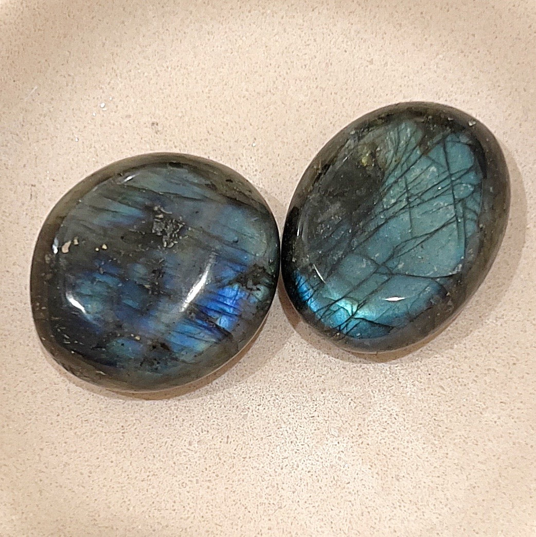 Two labradorite palm stones on neutral background with large blue flashes of colour. | Simply Esoteric
