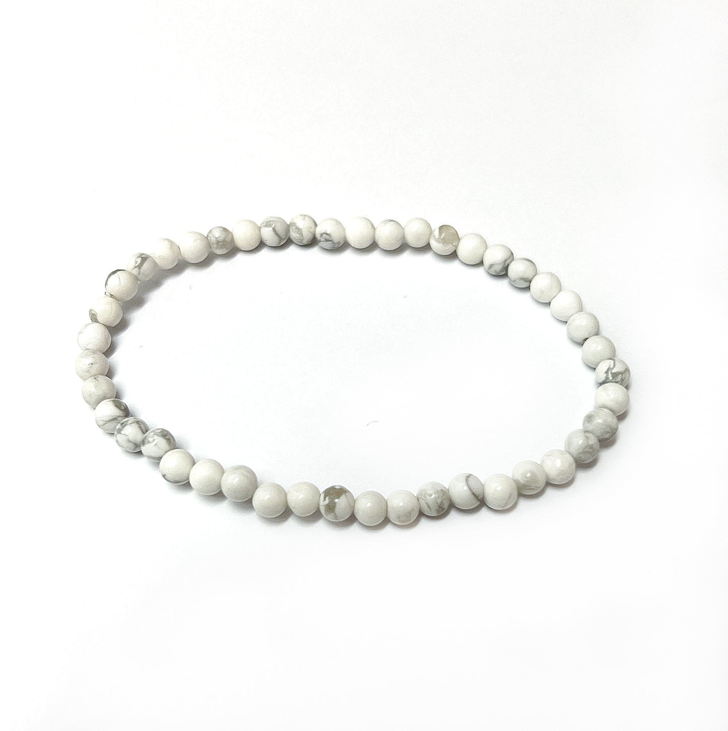 A White Howlite bead bracelet featuring 4mm beads with distinctive grey marbling, strung on an 18cm stretchy cord, symbolizing peace and mindfulness. | Simply Esoteric