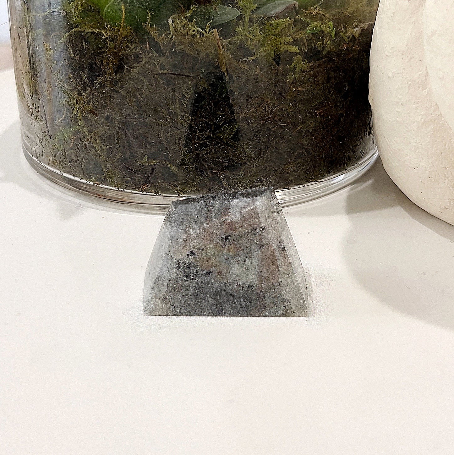 Labradorite Geolith measuring approximately 4cm x 3cm, featuring captivating orange and rainbow flashes, set against a background with a glass pot containing a succulent plant. | Simply Esoteric