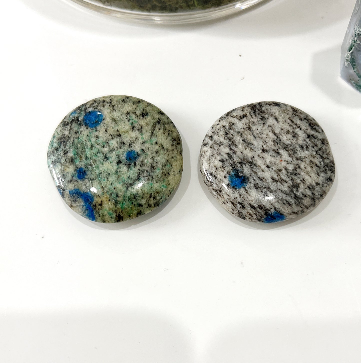 Two polished K2 Jasper worry stones with blue azurite inclusions against a granite background, each measuring approximately 4cm in diameter. | Simply Esoteric