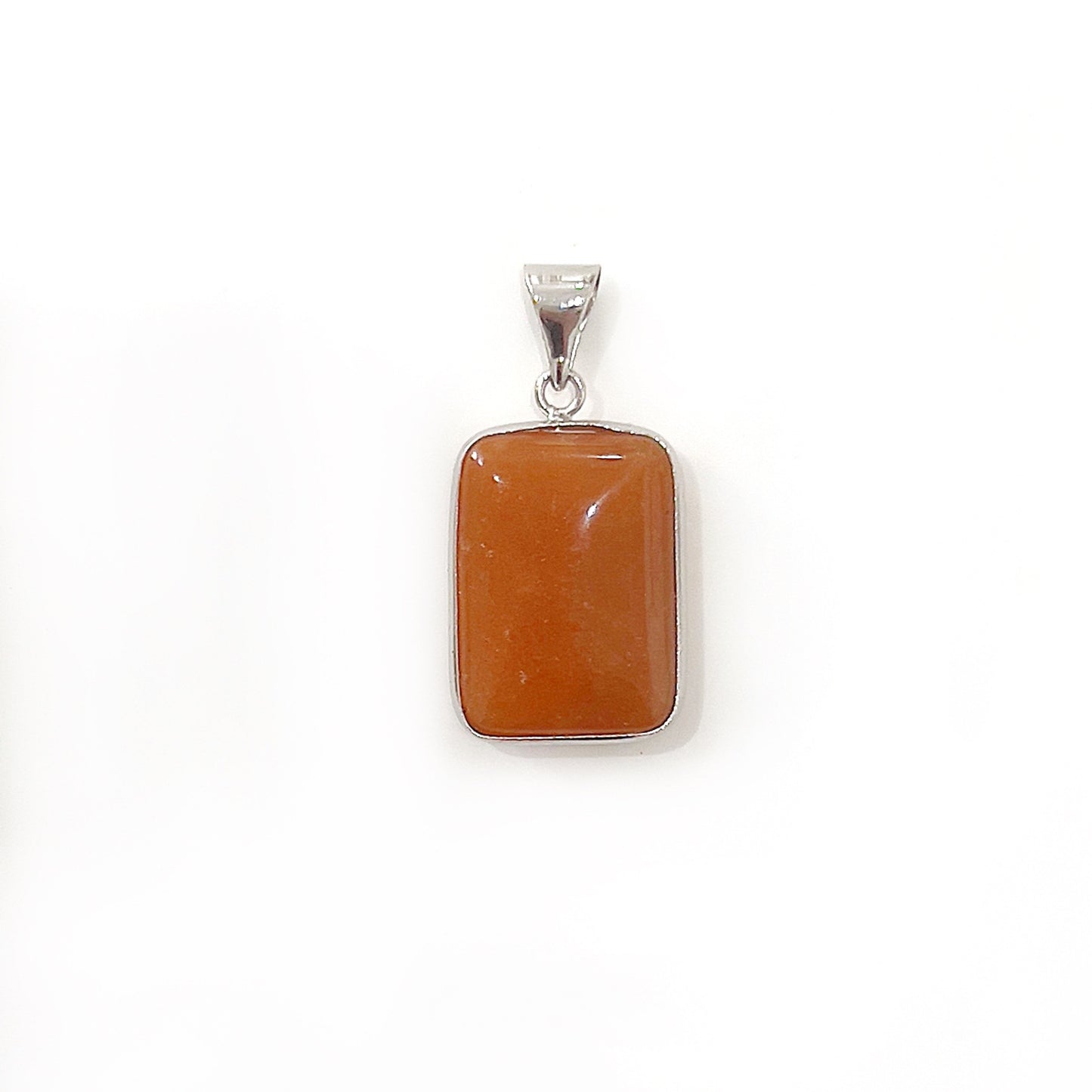 An elegant red jasper pendant with a polished silver setting and bail. The jasper stone is a warm, terracotta red, cut into a smooth rectangle, showcasing subtle marbling. Its simple yet classic design is presented against a white background, highlighting the natural beauty of the stone and the refined silver framework. | Simply Esoteric
