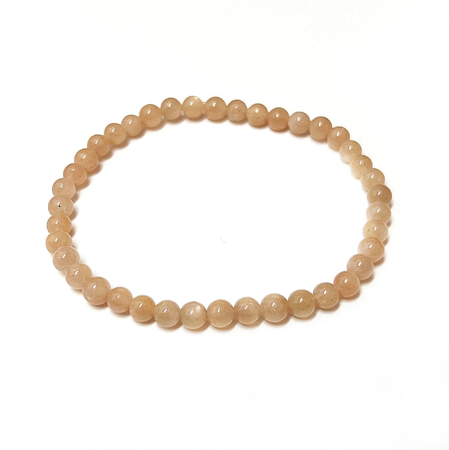 A delicate bracelet made of 5mm peach moonstone beads, presenting a soft, translucent peach hue with a gentle glow. The beads are uniformly sized and strung tightly together, forming a graceful circle against a white background, reflecting the subtle, soothing energy of the moonstone. | Simply Esoteric