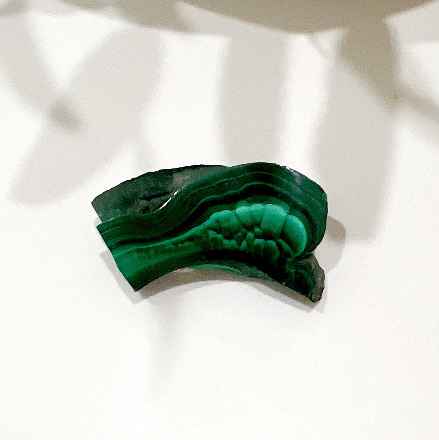 A polished malachite slice measuring 43mm x 22mm x 7mm, featuring intricate banding patterns in deep and vibrant green hues. | Simply Esoteric