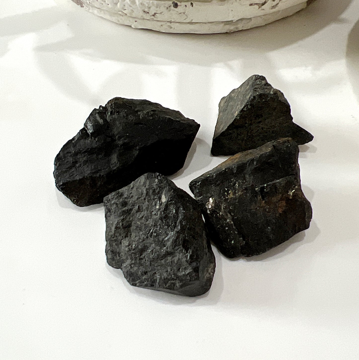 A collection of raw black tourmaline on neutral background | Simply Esoteric