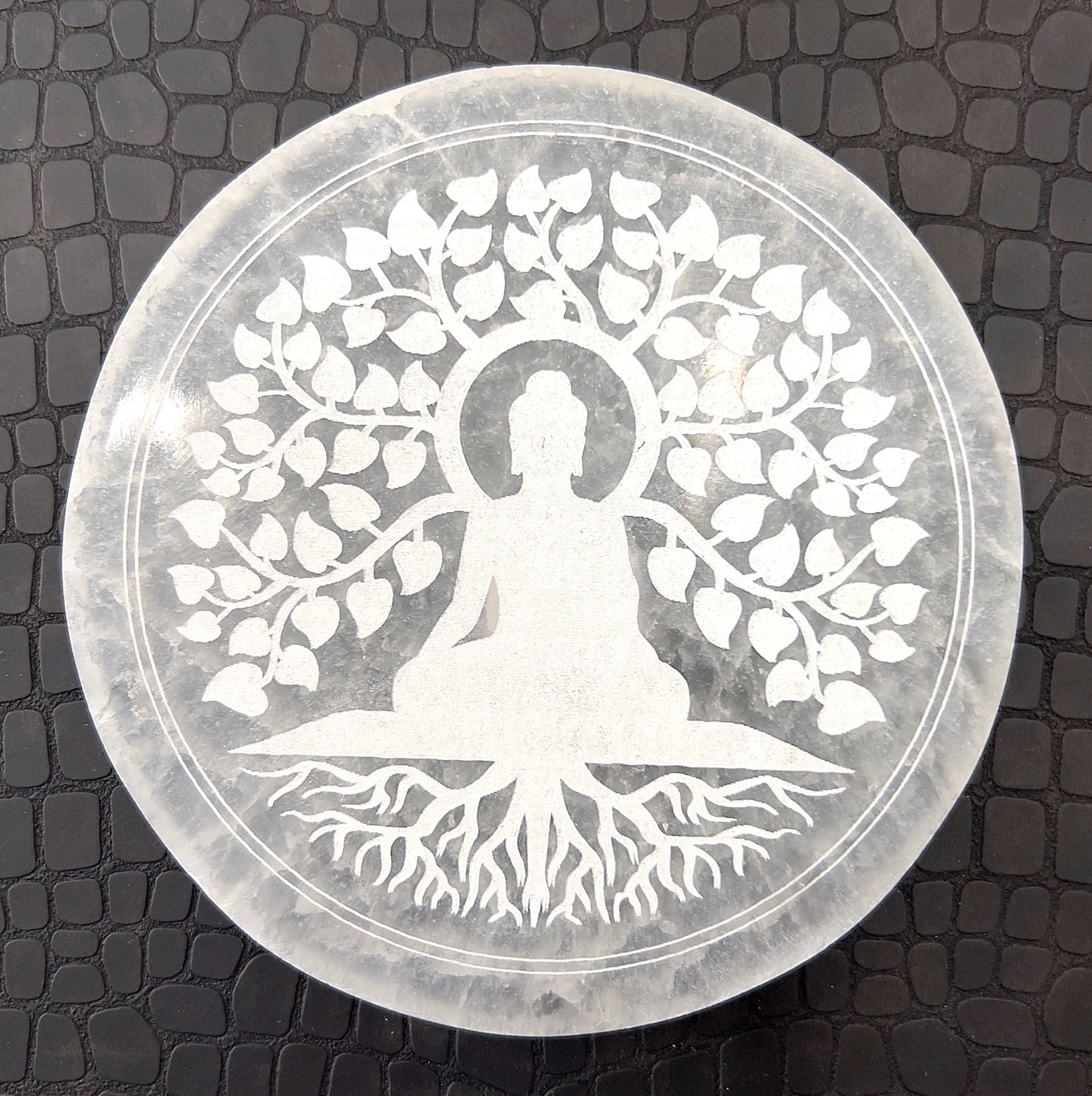 A polished selenite charging plate with a smooth, oval shape and a pearly white glow. Known for its energy-cleansing properties, the plate has a flat surface ideal for placing other crystals upon for purification and recharging, highlighted against a simple background that accentuates its pure, clean appearance. | Simply Esoteric