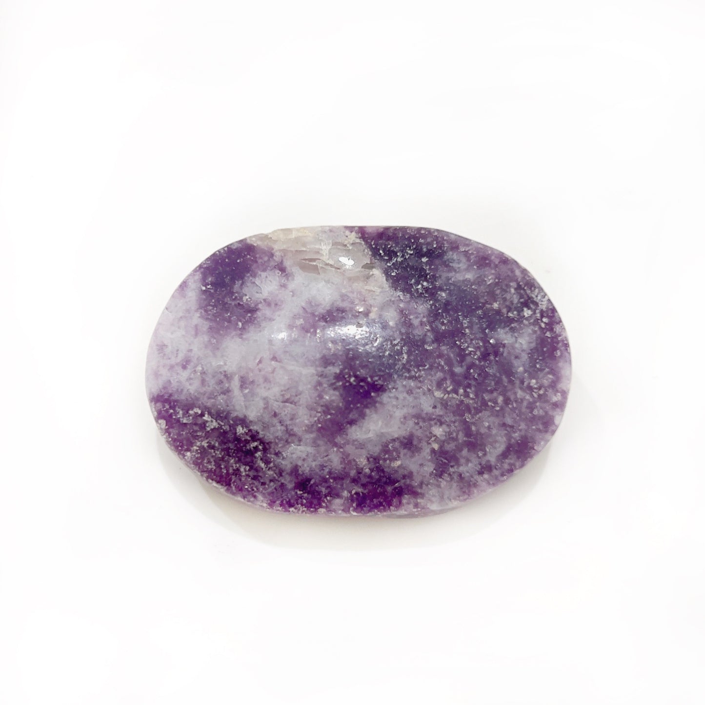 A polished lepidolite palm stone with a smooth, oval shape, displaying a rich lavender color sprinkled with glittering mica inclusions. The stone has a soft sheen and is set against a white background, highlighting its tranquil and soothing appearance. | Simply Esoteric