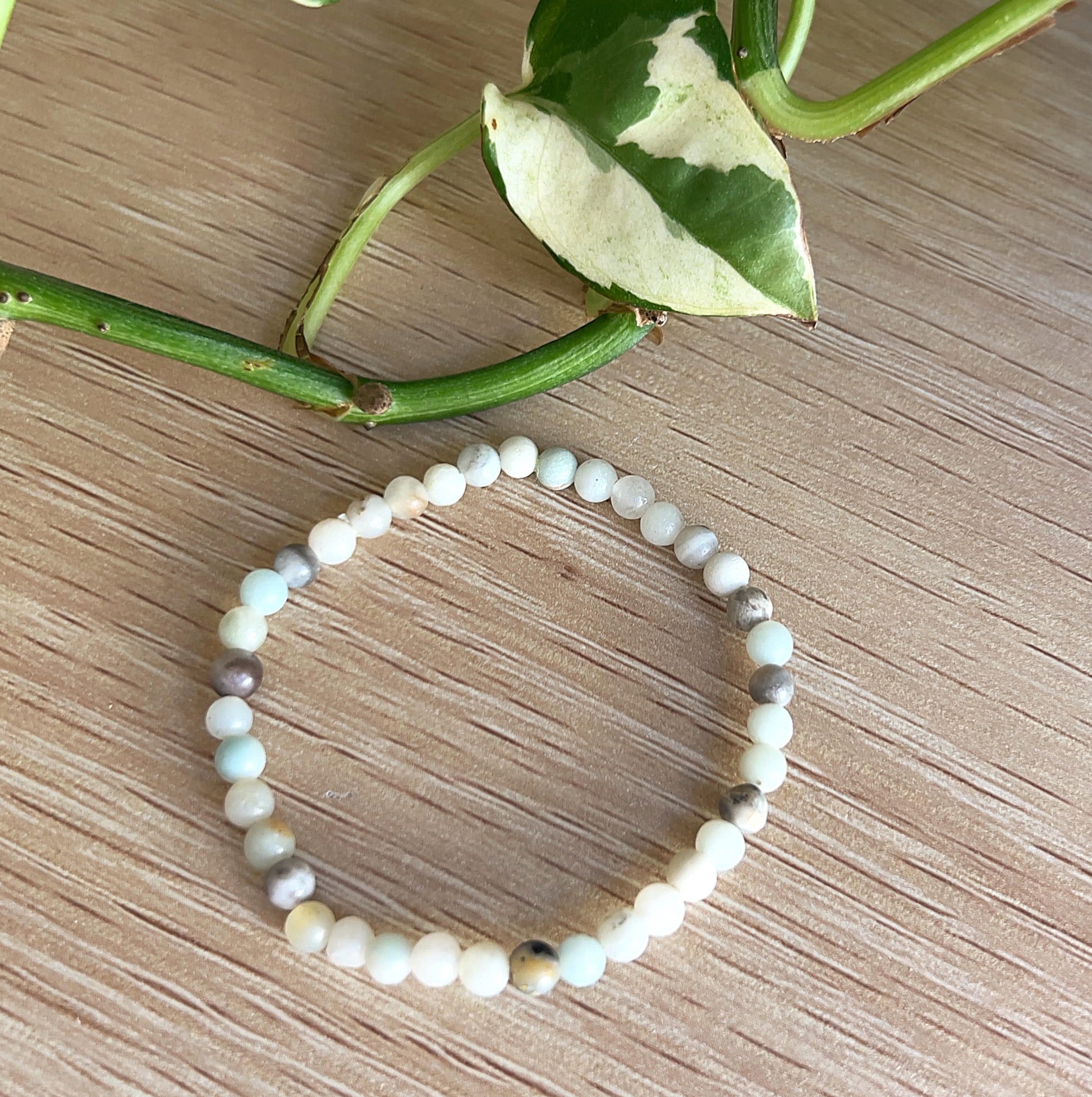 Amazonite Beaded bracelet on a wooden surface with green leaves in the background