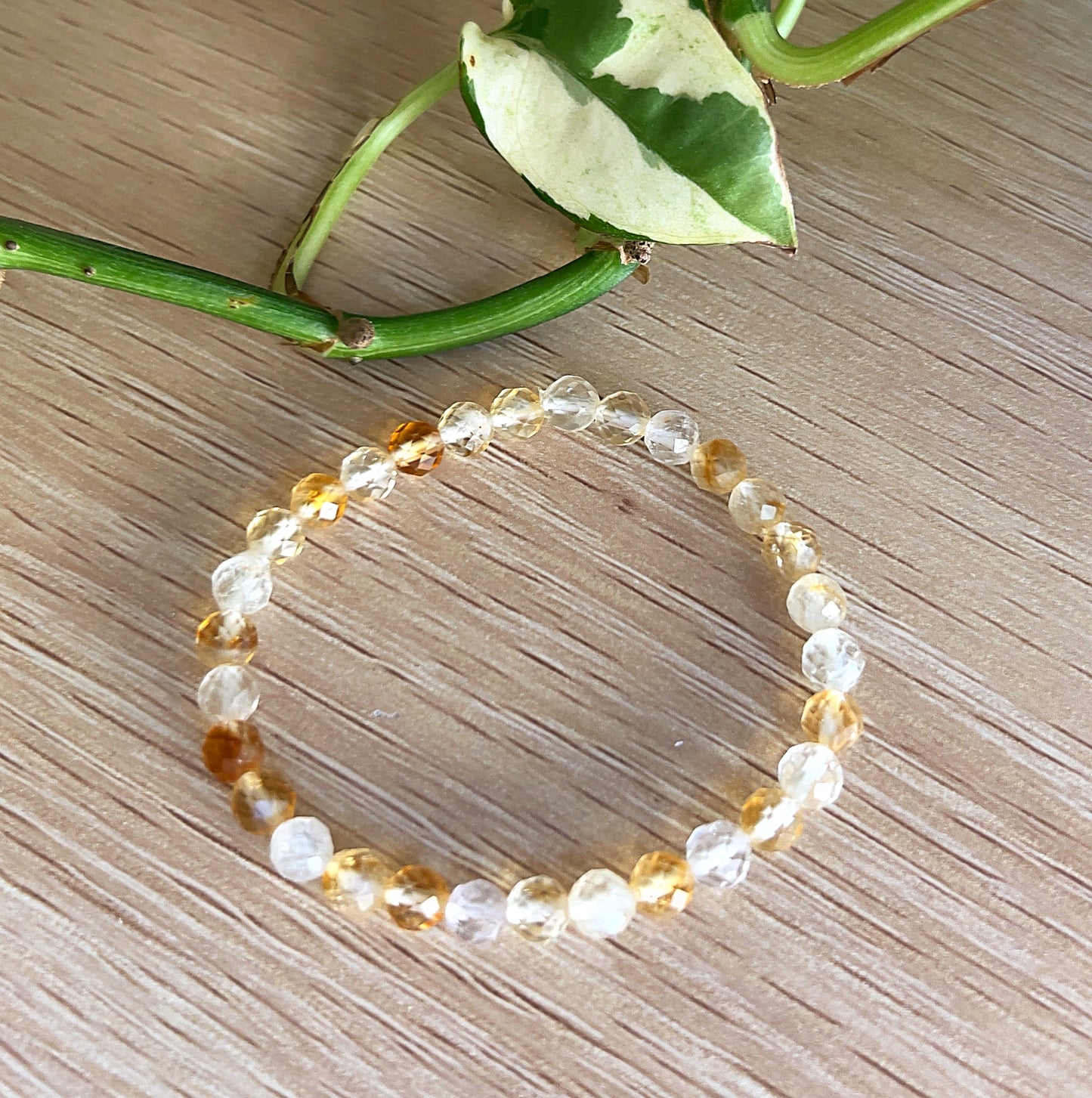 Citrine beaded bracelet (kids size) on a wooden surface with green leaves.