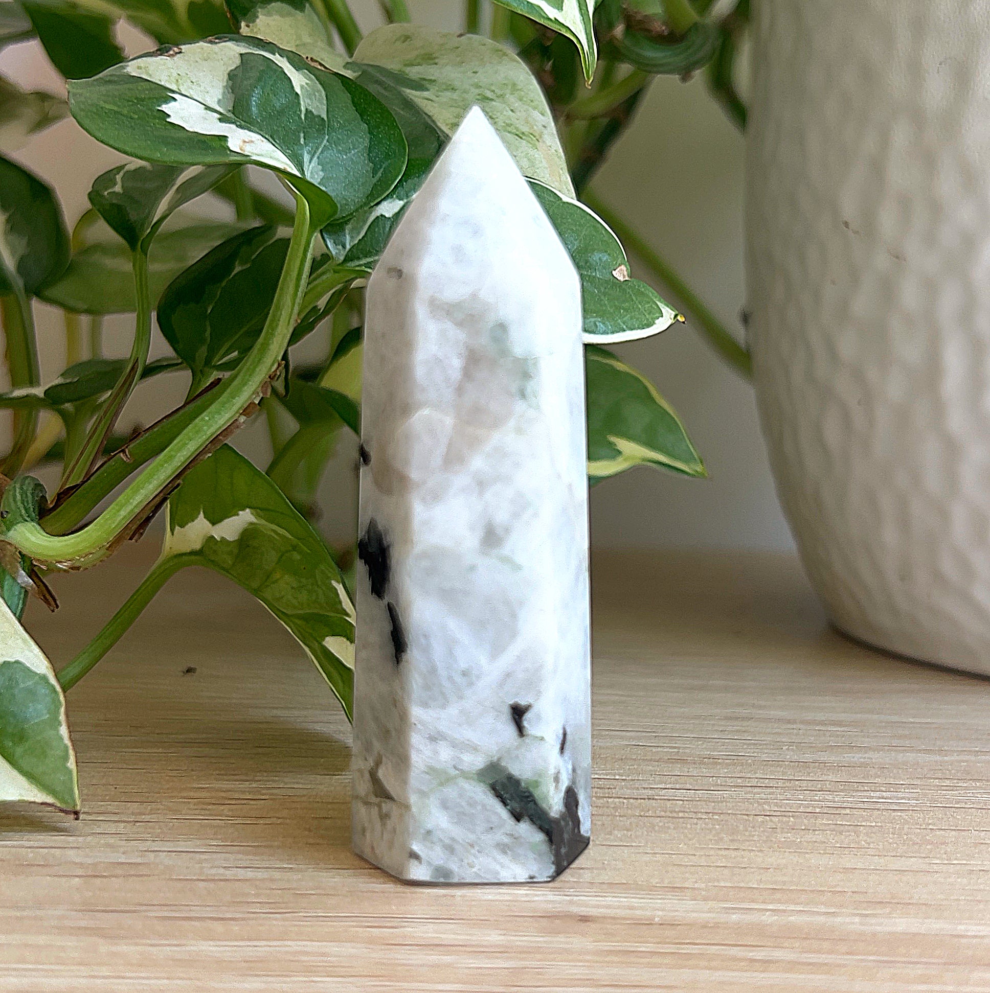 Moonstone tower on a wooden surface with a plant in the background