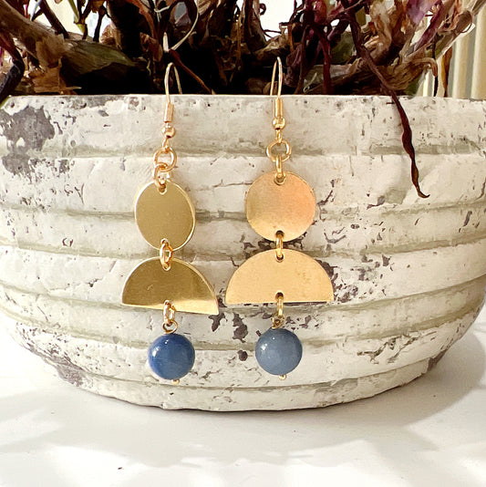 Gold-coloured earrings with geometric elements featuring 10mm blue aventurine beads, measuring 6.5cm in total length, displayed in front of a rustic plant pot. | Simply Esoteric