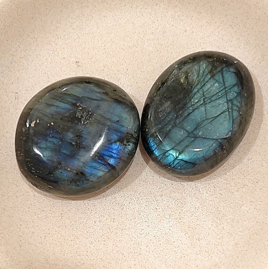 Two labradorite palm stones on neutral background with large blue flashes of colour. | Simply Esoteric