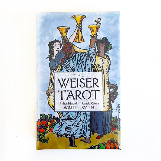 The Weiser Tarot Deck, illustrated by Pamela Colman Smith under the direction of Arthur Edward Waite, displays a vibrant box cover with a central illustration of three figures celebrating with golden cups, against a blue sky and floral background, symbolizing joy and community in tarot tradition. | Simply Esoteric