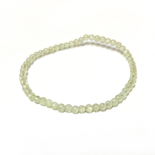 A delicate Prehnite bead bracelet with translucent pale green stones, approximately 3.5mm in size, strung on a stretchy cord to fit most wrists, measuring about 18cm in length. The bracelet's gentle color reflects a calm and soothing energy. | Simply Esoteric