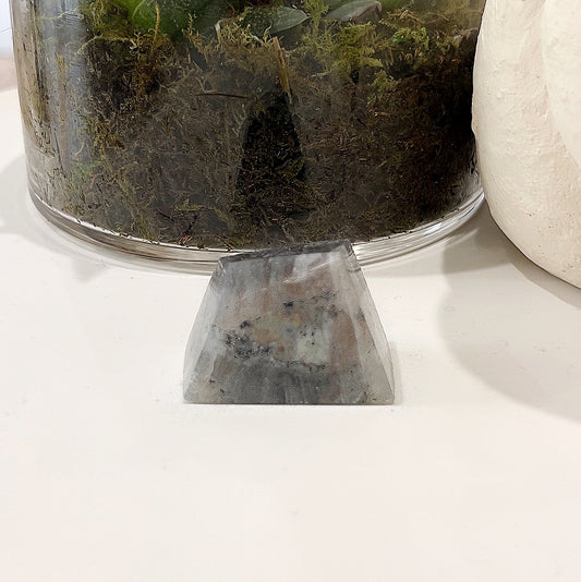 Labradorite Geolith measuring approximately 4cm x 3cm, featuring captivating orange and rainbow flashes, set against a background with a glass pot containing a succulent plant. | Simply Esoteric