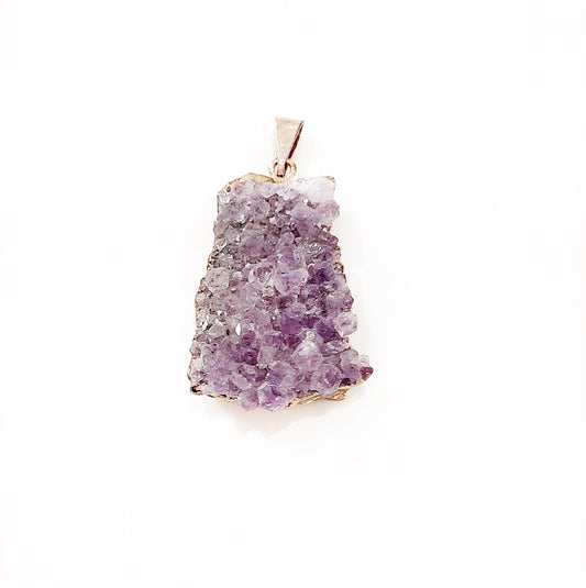 Amethyst cluster pendant featuring numerous tiny, sparkling purple crystals densely packed on a rough natural base, set with a simple metal bail for attachment to a necklace. The pendant showcases the raw and organic beauty of amethyst, with a jagged, uneven outline emphasizing its natural form. | Simply Esoteric