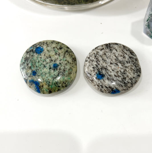 Two polished K2 Jasper worry stones with blue azurite inclusions against a granite background, each measuring approximately 4cm in diameter. | Simply Esoteric