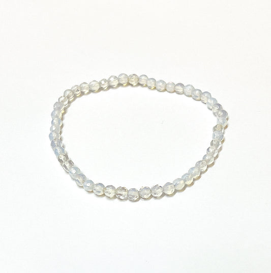 An Opalite bead bracelet with sparkling 4mm faceted beads, exhibiting a milky translucence with soft iridescent hues, on an 18cm stretchy cord, radiating a gentle yet powerful energy. | Simply Esoteric