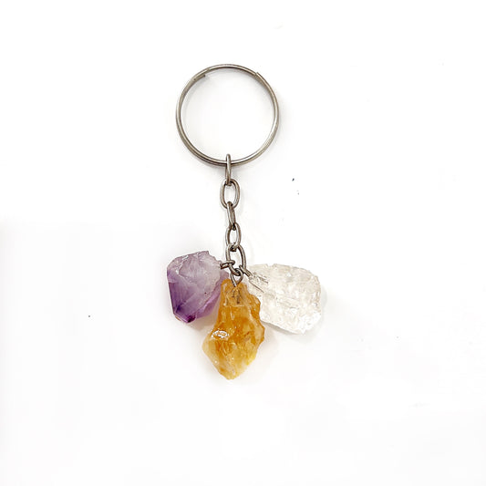 A keyring featuring a cluster of natural, unpolished crystals including a purple amethyst, golden citrine, and clear quartz, each with distinct rough textures. The crystals are attached to a simple metal chain and ring, combining rustic charm with everyday functionality. | Simply Esoteric