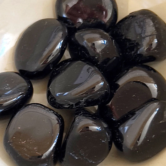 Smooth Black Tourmaline Tumble Stones, polished to reveal their deep black color, symbolizing protection and grounding against negative energies and electromagnetic pollution, perfect for carrying or placing in sacred spaces. | Simply Esoteric