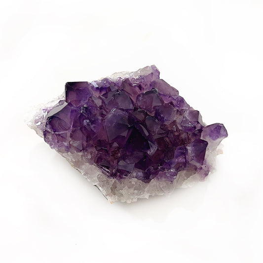 An exquisite amethyst crystal cluster featuring deep purple crystalline structures that emerge from a natural rock base, symbolizing calm, intuition, and spiritual protection. | Simply Esoteric