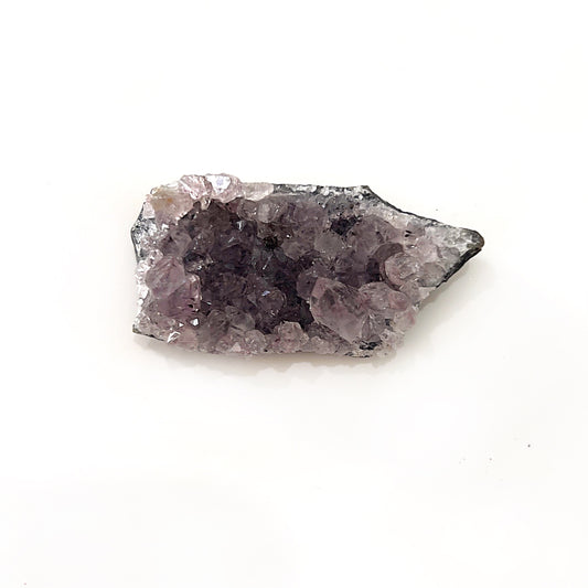 methyst crystal cluster featuring deep crystalline structures that emerge from a natural rock base, symbolizing calm, intuition, and spiritual protection. | Simply Esoteric