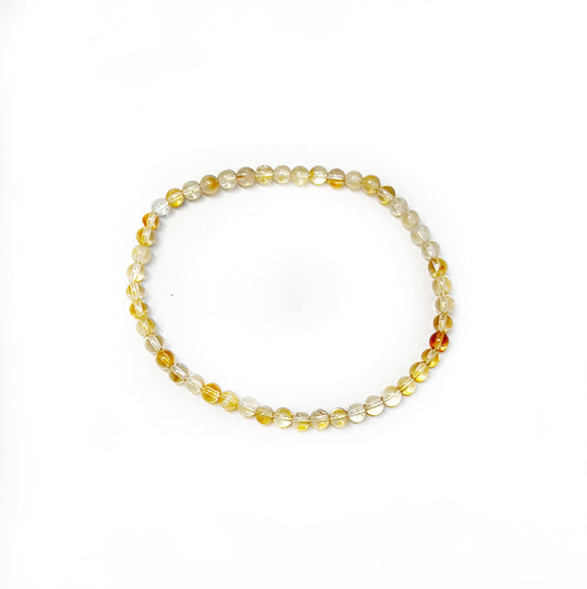 A vibrant citrine bead bracelet, featuring 4mm faceted beads with a spectrum of yellow hues from light lemon to deep gold, strung neatly on a stretchy cord for a snug fit around the wrist. The beads gleam with a translucent quality, capturing the light and adding a touch of elegance to the piece. | Simply Esoteric