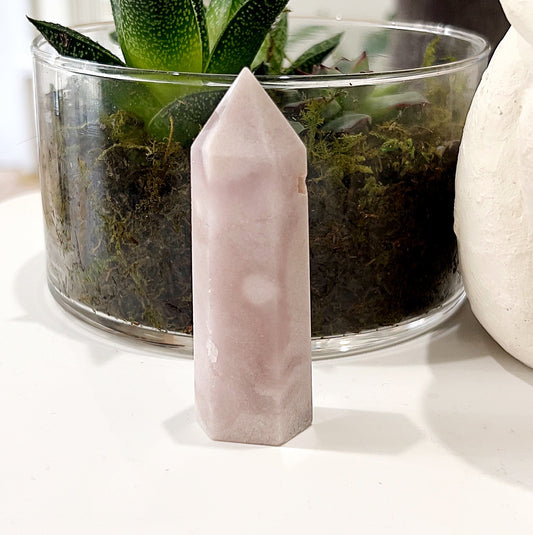 Pink Amethyst Tower measuring approximately 8cm, featuring soft pink hues, set against a background with a glass pot containing a succulent plant. | Simply Esoteric